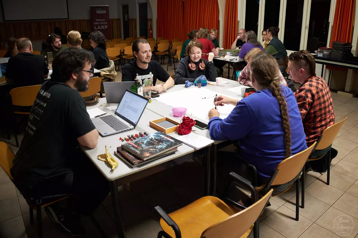 Een tafel met deelnemers die een tabletop RPG aan het spelen zijn.