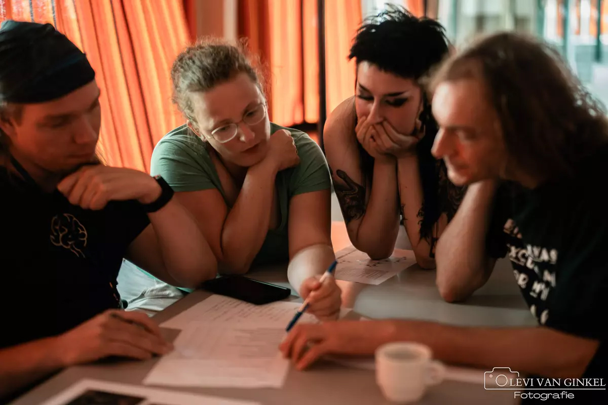 Een groepje deelnemers vullen een pubquiz formulier in.